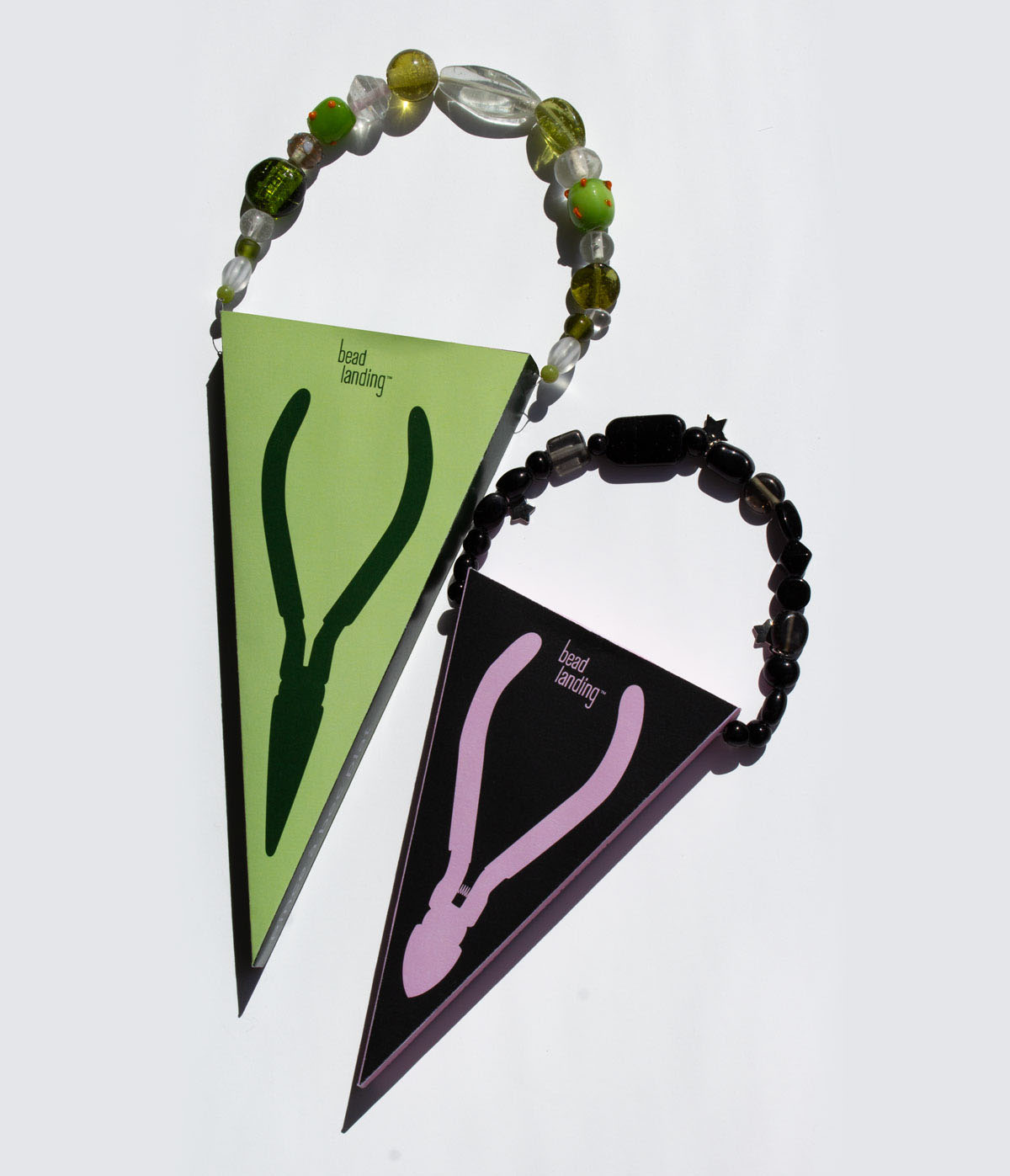 Deux emballages de pinces Bead Landing, l'un rose et noir et l'autre vert.